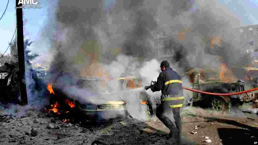 In this citizen journalism image, a firefighter hoses down burning vehicles after a Syrian air strike in Aleppo, Dec. 22, 2013.