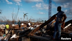 Pessoas limpam os destroços à volta das casas destruídas na sequência do ciclone Chido, em Mamoudzou, Mayotte, França, a 20 de dezembro de 2024.