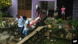 A covered body is removed from an apartment building where a woman and two men were executed in the Alta Progreso neighborhood of Acapulco, Mexico, Aug. 29, 2017. Both men were bound with tape, and all three were shot in the head at an apartment outfitted as an office for a taxi service.
