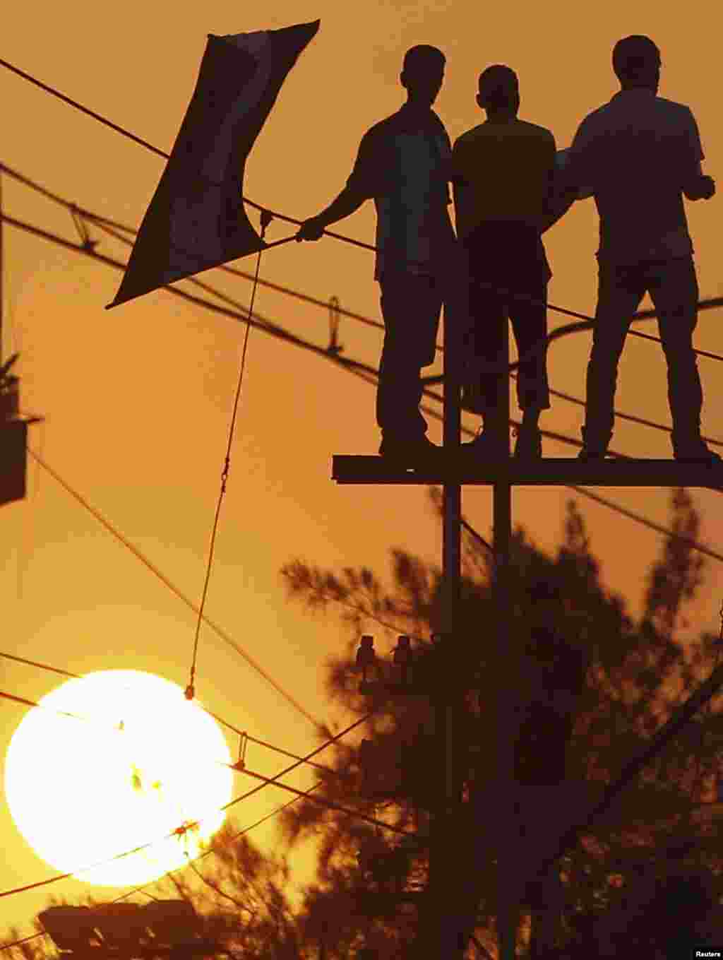 Protesters opposing Egyptian President Mohamed Morsi stand on top of an electric tram column and wave Egyptian flags during a protest in front of the presidential palace in Cairo, July 1, 2013. 