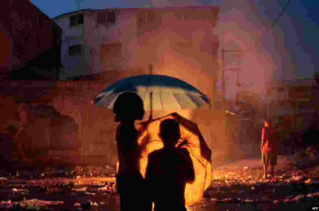 April 28: Haitian children watch a garbage fire during a rain storm, in Port-au-Prince, Haiti. (AP Photo/Dieu Nalio Chery)