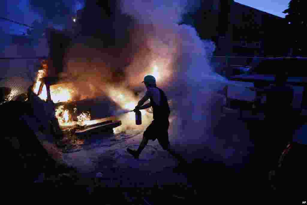 People attempt to extinguish cars on fire, Friday, May 29, 2020, in Minneapolis. Protests continued following the death of George Floyd, who died after being restrained by Minneapolis police officers on Memorial Day. (AP Photo/John Minchillo)