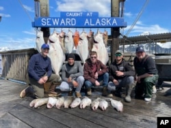 Captain John Moline, right, poses for a photo with others during the annual ASYMCA Alaska Combat Fishing Tournament on May 25, 2022, in Seward, Alaska. The tournament, which began in 2007 and now involves more than 300 soldiers, includes a day of deep-water fishing followed by a celebratory banquet with prizes for the largest catch, smallest catch and soldier who got the sickest. (Armed Services YMCA via AP)