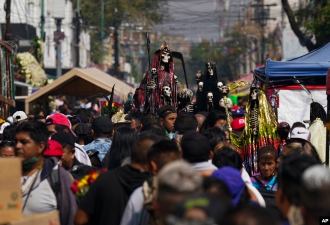 Devotos cargan estatuas ornamentadas de "La Santa Muerte", en el barrio de Tepito de la Ciudad de México, el martes 1 de noviembre de 2022.