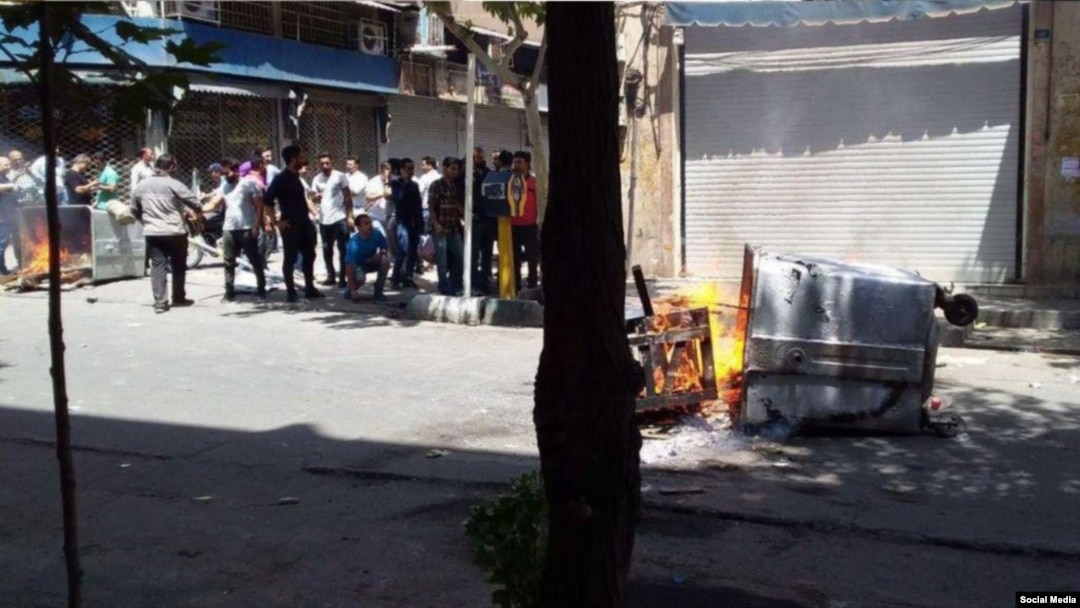 Para pengunjuk rasa anti-pemerintah yang marah dengan kondisi Iran yang makin memburuk membakar tempat-tempat sampah di distrik Laleh Zar, di Tehran, 26 Juni 2018.
