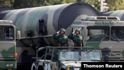 FILE PHOTO: PLA soldiers salute in front of nuclear-capable missiles during a parade in Beijing.