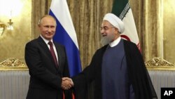 FILE - In this Nov. 1, 2017 file photo released by an official website of the office of the Iranian Presidency, Iran's President Hassan Rouhani, right, shakes hands with Russian President Vladimir Putin, at the Saadabad Palace in Tehran.