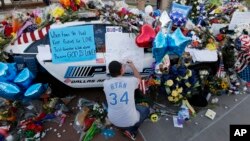 Tracy St. Romain leaves a note on a patrol car at a makeshift memorial in front of the Dallas (Texas) police department, July 9, 2016. The memorial honors five officers fatally shot by a sniper Thursday evening. 