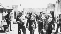 Field Marshal Erwin Rommel, center, walking through a desert village in Egypt