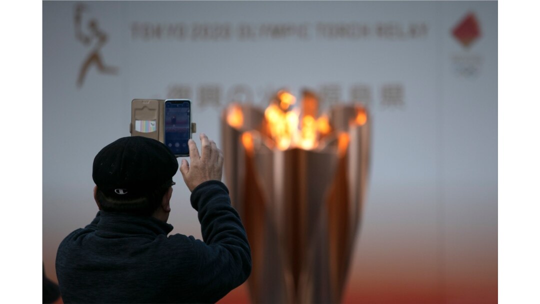 A man takes pictures of the Olympic Flame during a ceremony in Fukushima City, Japan, March 24, 2020.