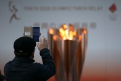 A man takes pictures of the Olympic Flame during a ceremony in Fukushima City, Japan, March 24, 2020.