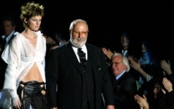 FILE - Italian designer Gianfranco Ferre, right, acknowledges applause on the catwalk with top model Stella Tennant, in Milan, March 2, 2003.