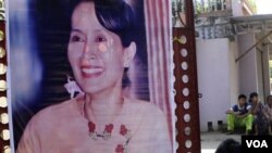 Seorang pendukung Aung San Suu Kyi memasang posternya di depan markas partai di Rangoon, Birma.