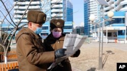 북한 평양의 보안원들이 신문을 읽고 있다. (자료사진)