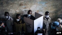 Le président de la République centrafricaine Faustin Archange Touadera dans un isoloir entouré par la garde présidentielle au bureau de vote du lycée Barthélemy Boganda dans le 1er district de Bangui, en RCA, le 27 décembre 2020