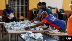 Polling station officials arrange marked ballots before proceeding to the counting at a voting station in Windhoek, Namibia, on December 1, 2024, during extended voting following the country's general election.