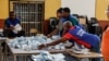 Polling station officials arrange marked ballots before proceeding to the counting at a voting station in Windhoek, Namibia, on December 1, 2024, during extended voting following the country's general election.