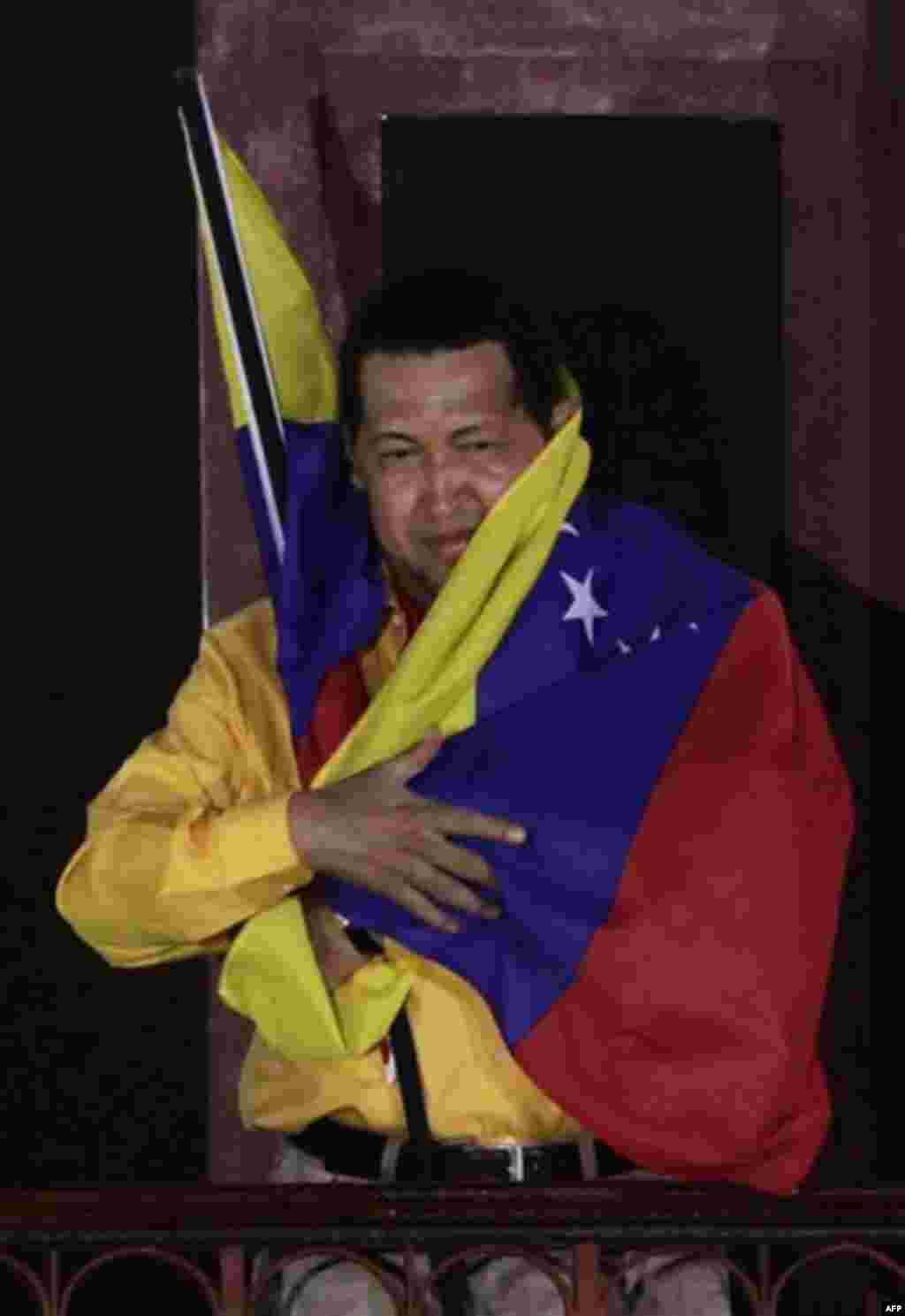 Venezuela's President Hugo Chavez wraps himself with a Venezuelan flag at a balcony of Miraflores presidential palace in Caracas, Venezuela, Thursday, July 28, 2011. Chavez sang on a balcony of the presidential palace as he celebrated his 57th birthday be