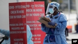 A health care worker carries a stack of clipboards at a COVID-19 testing site sponsored by Community Heath of South Florida at the Martin Luther King, Jr. Clinica Campesina Health Center, during the coronavirus pandemic, July 6, 2020.