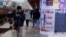 A man checks his smartphone outside a store promoting the Apple iPhone products in the southern Chinese city of Shenzhen, Jan. 26, 2016. 