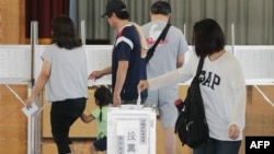 A woman (R) casts her ballot as residents vote to elect a new governor, in the city of Urasoe in Okinawa on September 30, 2018. Residents of Okinawa were voting for a new governor on Sept. 30 in an election seen as decisive for the future of the US milita