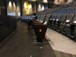FILE - A graduate assistant sits in an empty auditorium during an online lecture on the first day of classes, Aug. 17, 2020, at Georgia Tech in Atlanta.