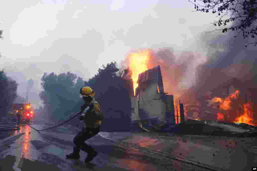 Un bombero lucha contra el incendio en Palisades que avanza mientras quema una estructura en el vecindario Pacific Palisades de Los Ángeles, el 7 de enero de 2025.