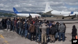 Migrantes guatemaltecos deportados desde Texas esperan en la pista del Aeropuerto Internacional La Aurora de Ciudad de Guatemala el 8 de diciembre de 2021.