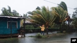 A man fixes the roof of a home surrounded by floodwaters brought on by Hurricane Eta in Wawa, Nicaragua, Nov. 3, 2020.