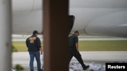 Dos miembros del Servicio de Inmigración y Aduanas de EE. UU. revisan equipajes que subirán a un avión en Brownsville, Texas, el 18 de mayo de 2019.