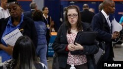 FILE - People speak with recruiters at a job fair in Uniondale, New York, Oct. 7, 2014.