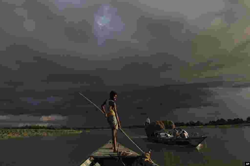 A boat carries flood relief materials as monsoon clouds surrounded the flood affected Gagalmari village in Assam state, India, July 2, 2012. 