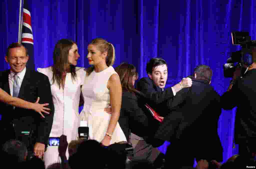 An unidentified man (3rd R) is forced off the stage by security staff after Australia&#39;s conservative leader Tony Abbott&#39;s (L) victory speech at an election night function in Sydney.