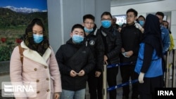 FILE - Chinese travelers wearing face masks to protest against the coronavirus undergo a health screening upon arrival at an Iranian airport in this undated photo published by IRNA on Jan. 30, 2020 (Credit: IRNA)