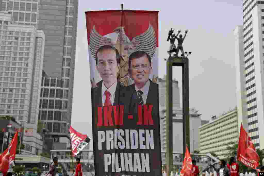 Spanduk berisi foto Presiden Joko Widodo dan Wakil Presiden Jusuf Kalla dalam parade di Jakarta (17/10). (AP/Dita Alangkara)