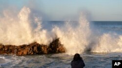 FILE - A woman photographs big waves in Port Elizabeth, South Africa, Sunday, Sept. 17, 2023. S