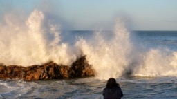 FILE - A woman photographs big waves in Port Elizabeth, South Africa, Sunday, Sept. 17, 2023. S
