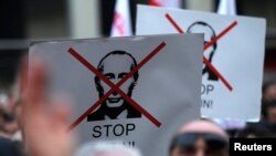 People hold banners during an opposition rally to protest against Russia's policy toward Georgia and Ukraine in Tbilisi, Nov. 15, 2014.