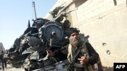 An armed jihadist stands next to the wreckage of a Syrian government forces aircraft which was shot down by militants of the Islamic State (IS) group over the Syrian town of Raqa on September 16, 2014. 