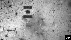 FILE - In this Feb. 22, 2019, file photo, this image released by the Japan Aerospace Exploration Agency (JAXA) shows the shadow, center above, of the Hayabusa2 spacecraft after its successful touchdown on the asteroid Ryugu.