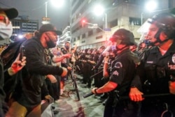 In this May 29, 2020, photo, protesters confront police officers during a protest over the death of George Floyd in Los Angeles. Floyd died in police custody Monday in Minneapolis.
