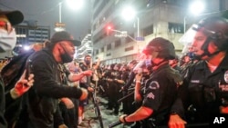 In this May 29, 2020, photo, protesters confront police officers during a protest over the death of George Floyd in Los Angeles. 