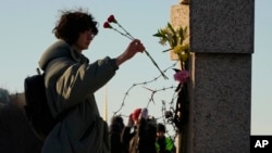 Una mujer deposita flores mientras la gente rinde homenaje a Alexei Navalny en el Memorial a las Víctimas de la Represión Política en San Petersburgo, Rusia, el 18 de febrero de 2024.