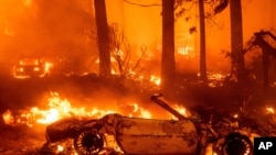 Flames consume vehicles as the Dixie Fire tears through the Indian Falls community in Plumas County, Calif., July 24, 2021.