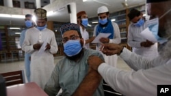 A student receives a COVID-19 vaccine from a health worker at a vaccination center at Jamia Naeemia, an Islamic university in Lahore, Pakistan, July 12, 2021.