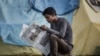 FILE - An earthquake survivor reads a newspaper at a shelter camp in Kathmandu, April 29, 2015.