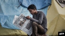 FILE - An earthquake survivor reads a newspaper at a shelter camp in Kathmandu, April 29, 2015.