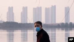 FILE - A man stands along the waterfront in Wuhan, China, Jan. 30, 2020. Arek and Jenina Rataj were starting a new life in Wuhan when a viral outbreak spread across the city of 11 million. Arek felt compelled to document the outbreak.