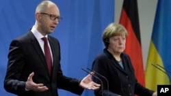 Ukrainian Prime Minister Arseniy Yatsenyuk and German Chancellor Angela Merkel talk to reporters at the chancellery in Berlin, Jan. 8, 2015.