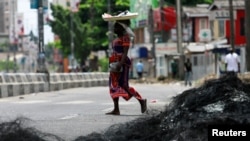 A woman walks past the remains of a barricade in Surulere area of Lagos, Nigeria, Oct. 23, 2020. 